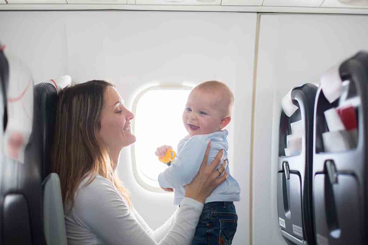 Young mom, playing and breastfeeding her toddler boy on board of aircraft
